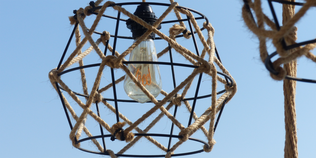 Eine Lampe welche aus der GlÃ¼hbirne, einem schwarzen Drahtgestell, umwickelt von Seilen besteht.